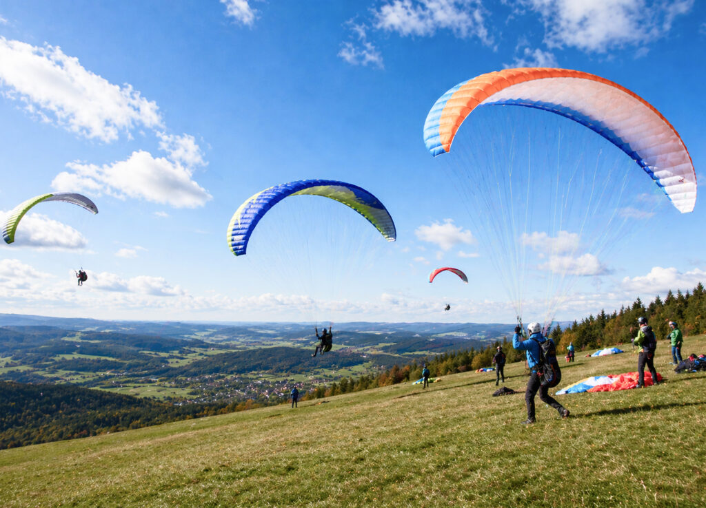 Mehrere Paraglider üben die ersten Schritte des fliegens.
